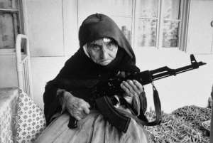 A 106-year-old Armenian woman sits in front of her home guarding it with a rifle, in the village of Degh, near the border of Azerbaijan. 1990.